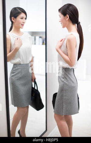 Young Chinese woman examining herself in front of mirror Stock Photo