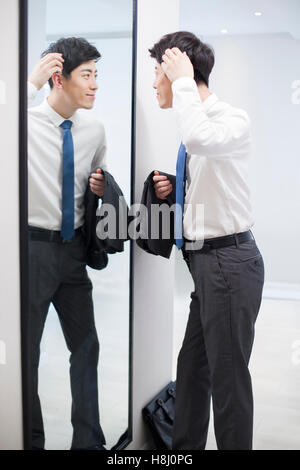 Young Chinese man examining himself in front of mirror Stock Photo