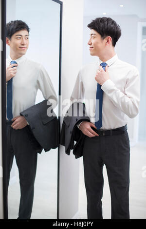 Young Chinese man examining himself in front of mirror Stock Photo