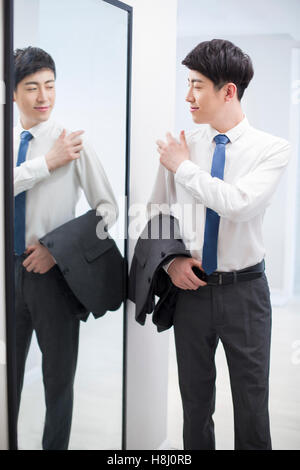 Young Chinese man examining himself in front of mirror Stock Photo