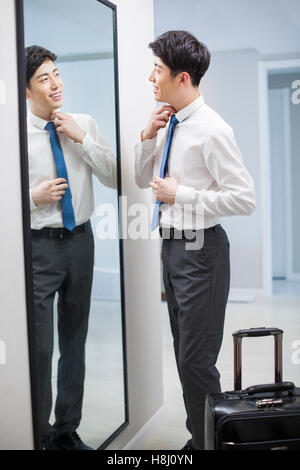 Young Chinese man examining himself in front of mirror Stock Photo