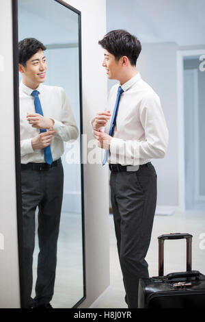 Young Chinese man examining himself in front of mirror Stock Photo