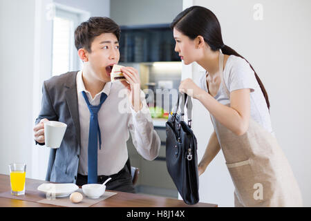 Young Chinese businessman having breakfast in a hurry Stock Photo