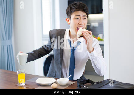 Young Chinese businessman having breakfast in a hurry Stock Photo