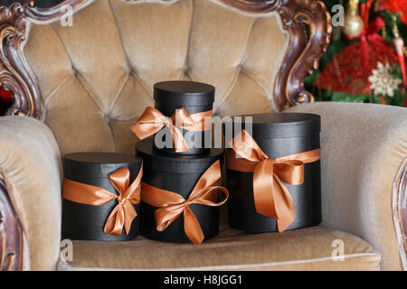 Wrapped gift black boxes with ribbons as Christmas presents on a chair Stock Photo