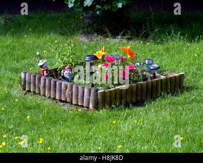 lawn ornaments on grass surrounded by wooden edge Stock Photo