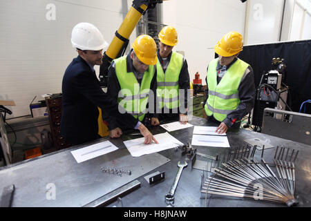 Workers and manager in safety helmets working with documents at factory Stock Photo