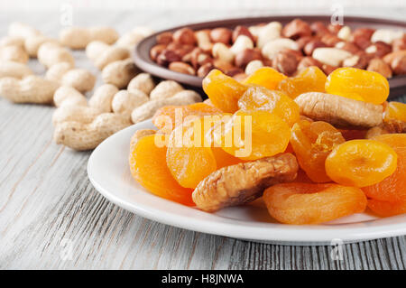 Dried fruits and nuts on a wooden background. Candied fruits, lemon, apricot, fig and nuts in plate. Stock Photo