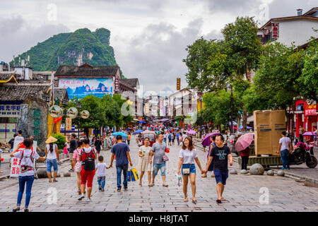 View over downtown of Yangshuo with people on the street and recognizable karst peaks in the background Stock Photo