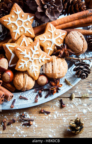 Christmas decor with homemade gingerbread cookies stars, cones, nuts and Christmas spices over rustic wooden background Stock Photo