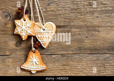 Gingerbread Christmas cookies hanging over wooden background with copy space - festive Christmas pastry and decor Stock Photo