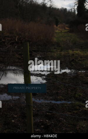 private property barbed wire fence in front of muddy puddles Stock Photo