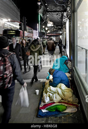 LONDON Homeless man and begging cup with his entire belongings inc. bedding living and sleeping on Shaftesbury Avenue London UK Stock Photo