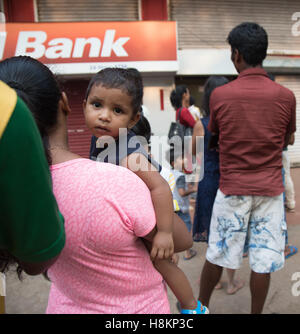 Goa, India. Monday 14th November 2016. Child waits in ATM queue. Banking chaos continues with long queues at any ATMs which are still open. A strict withdrawal limit of 2500 rupees ( approx £30) per day has been set for ATMs but even then many run out of cash within a few hours each day. Credit:  WansfordPhoto/Alamy Live News Stock Photo