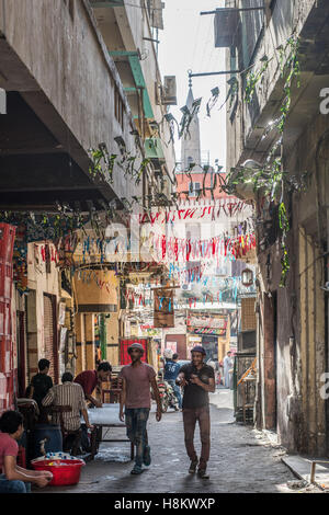 Cairo, Egypt. Men sitting in and walking through an alleyway in the outdoor bazaar/ flea market Khan el-Khalili in Cairo. Stock Photo