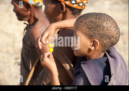 Portrait of San or Bushman child playing with Acacia flowers Stock Photo