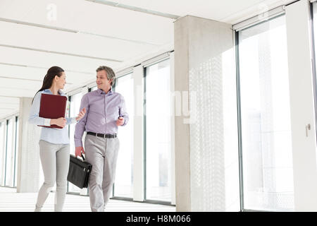 Businessman and businesswoman talking while walking in new office Stock Photo