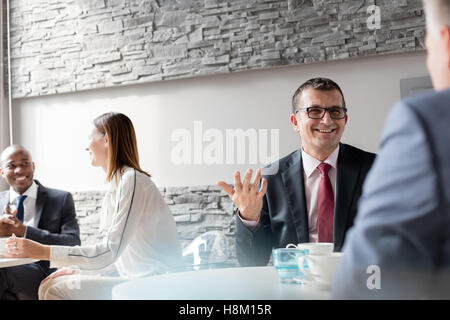 Smiling mature man talking with male colleague in office cafeteria Stock Photo