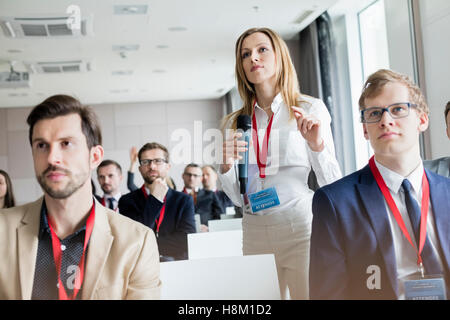 Confident businesswoman gesturing while holding microphone during seminar Stock Photo