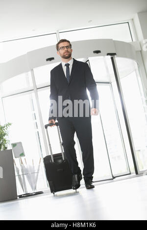 Confident businessman with luggage entering convention center Stock Photo