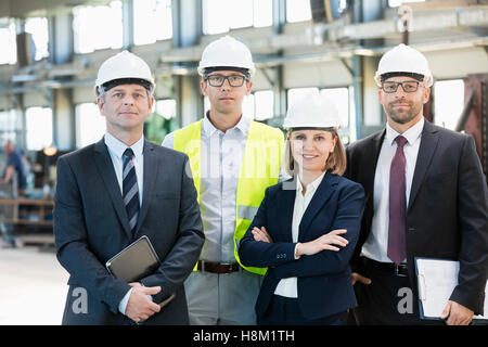 Team of confident business people wearing hardhats in metal industry Stock Photo