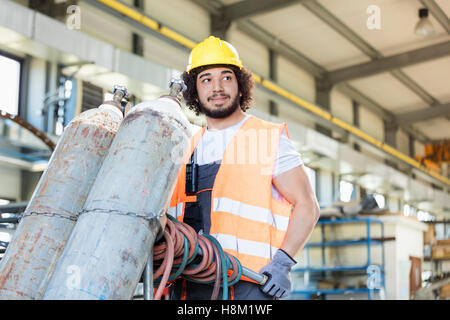 Young manual worker moving gas cylinders in metal industry Stock Photo