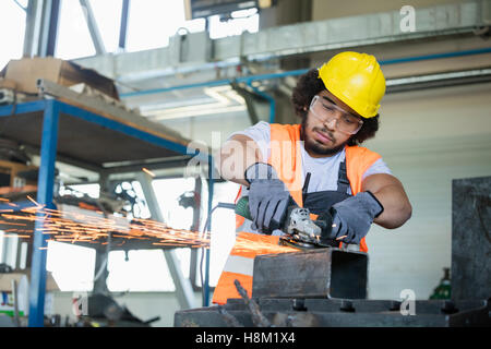 Young manual worker in protective workwear cutting metal in industry Stock Photo