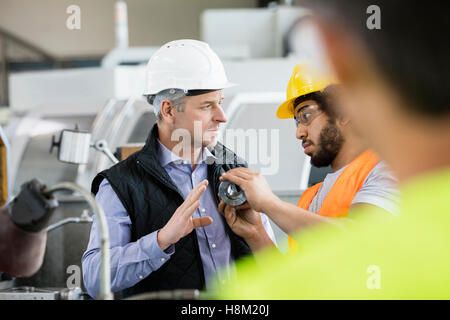 Male inspector having discussion with worker in metal industry Stock Photo