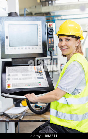 Portrait of female worker operating machinery at control panel in factory Stock Photo