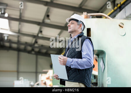 Side view of male supervisor holding clipboard in metal industry Stock Photo