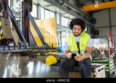 Young manual worker using mobile phone in metal industry Stock Photo
