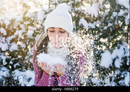 beautiful young woman holding a snow and blowing on it Stock Photo