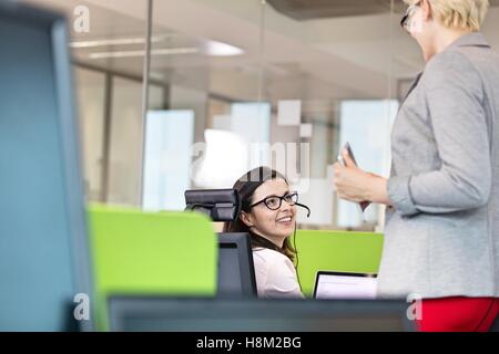 Female customer service representative talking with manager in office Stock Photo