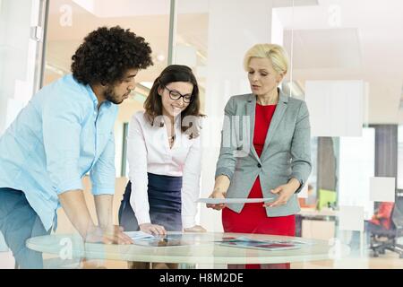 Mature businesswoman with colleagues discussing over project at table in office Stock Photo