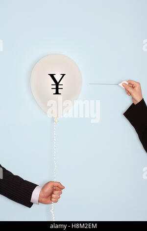 Cropped hands holding needle and popping balloon Stock Photo