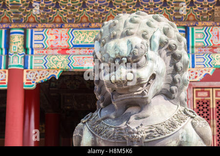 Beijing China - Detail of a bronze guardian lion statue (Shi) with the ornamented architecture of the Palace Museum in the backg Stock Photo