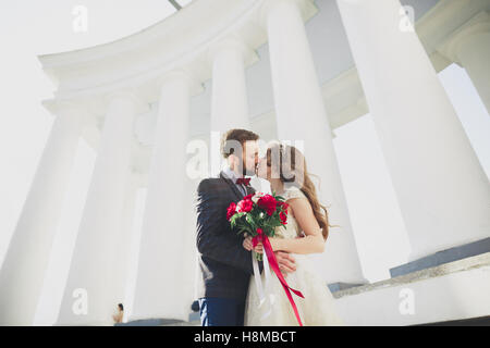 Beautiful couple, bride and groom posing near big white column Stock Photo