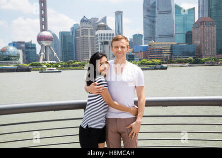 Portrait of smiling couple standing by railing with Shanghai skyline in background Stock Photo