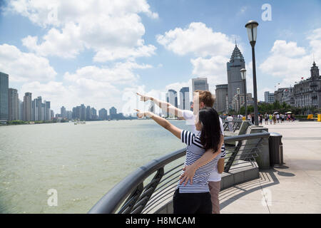 Couple pointing at cityscape while standing on promenade in Shanghai Stock Photo