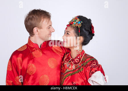 Mixed Race Bride and Groom in Studio wearing traditional Chinese wedding outfits Stock Photo