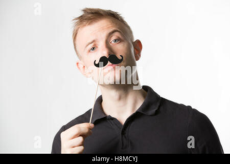 Portrait of an attractive young man wearing a retro style fake mustache. Stock Photo