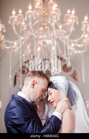 Side view of loving wedding couple standing head to head in church Stock Photo