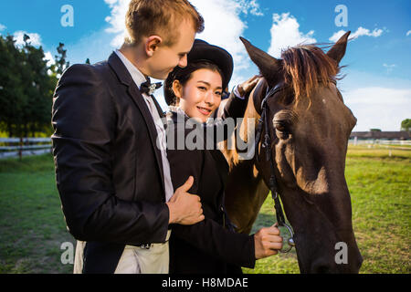 Portrait of smiling woman standing with man by horse on field Stock Photo