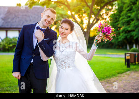 Portrait of happy wedding couple holding hands while standing at lawn Stock Photo