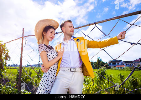 Thoughtful couple standing by fence on field against sky Stock Photo