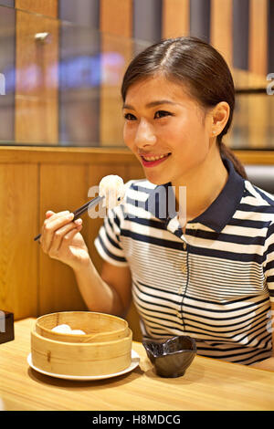 Chinese Woman eating Steamed dumpling in restaurant Stock Photo