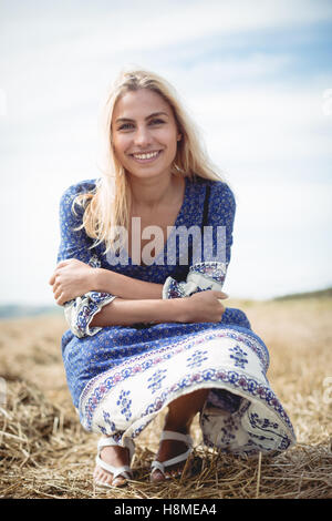 Smiling blonde woman crouching in field Stock Photo