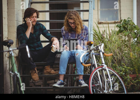 Couple talking on mobile phone and using digital tablet Stock Photo