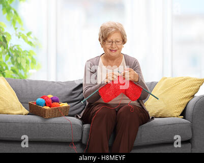 Elderly woman sitting on a sofa and knitting Stock Photo