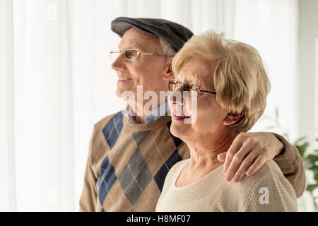 Mature man and woman looking through a window Stock Photo